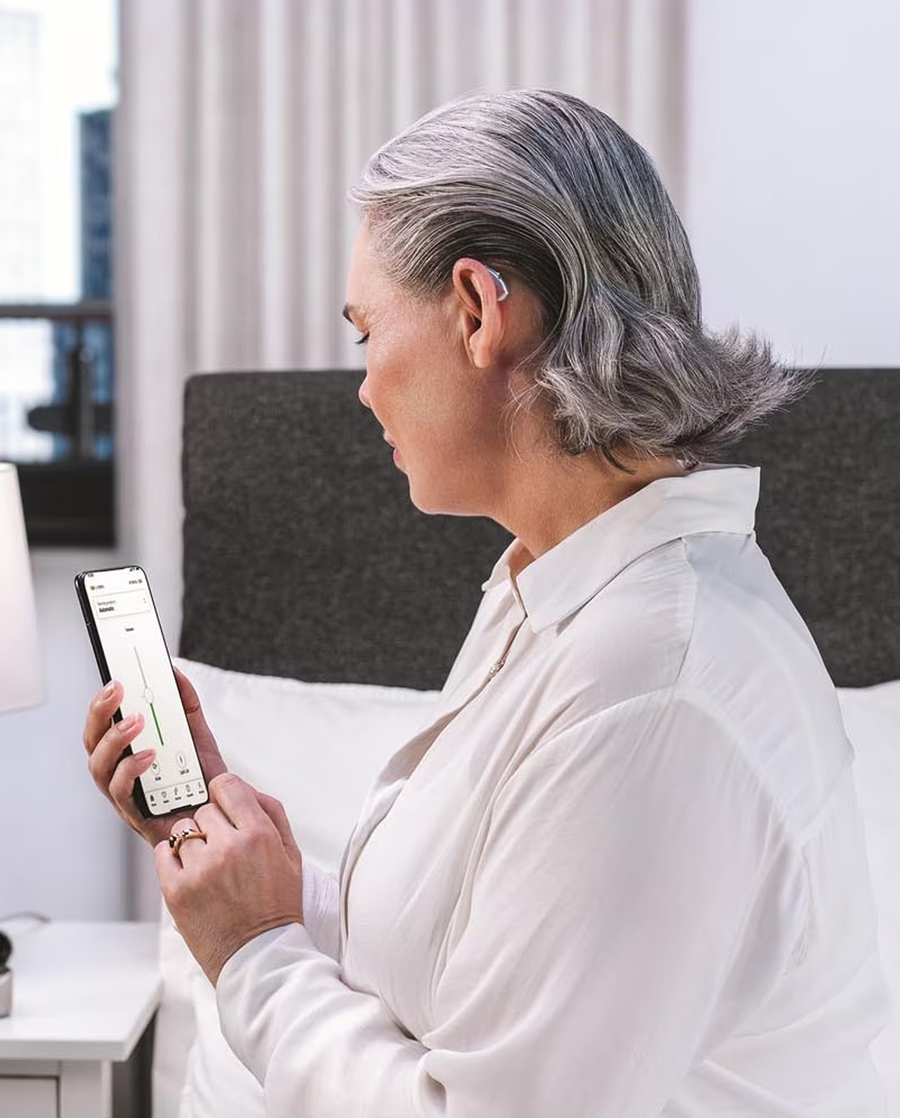 Person wearing a hearing aid and using a phone app